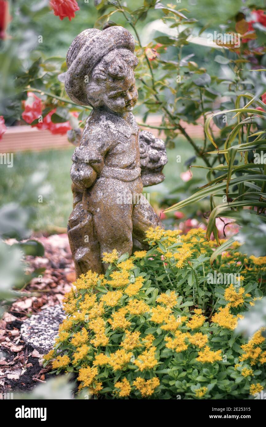 Sculpture of a little boy among the flowers in a garden border somewhere in the Netherlands Stock Photo