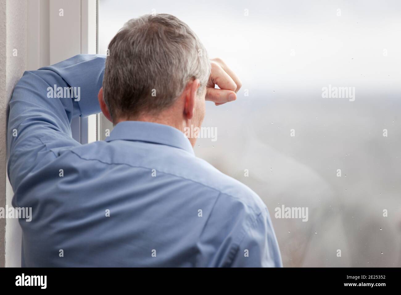 Tired or sorrowful businessman looking out of a window - focus on the hand and the window Stock Photo
