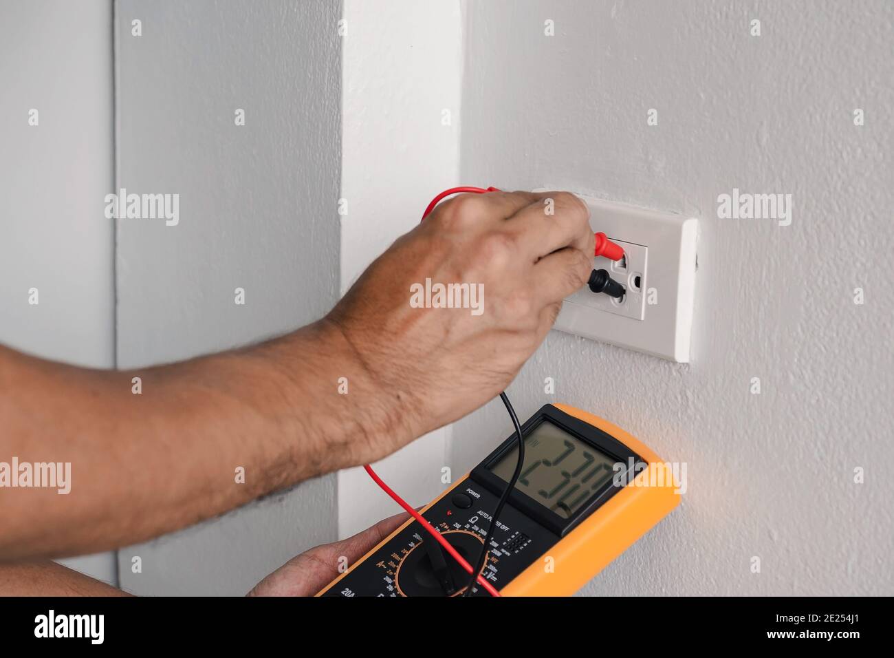 Electrician is using a digital meter to measure the voltage at the