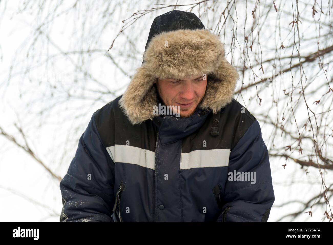 Portrait of a man in a hat with light fur with a blue winter jacket at the workplace Stock Photo