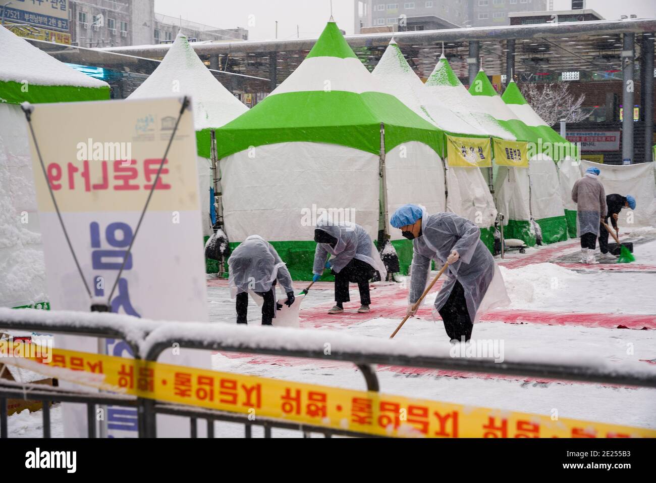 Bucheon, Bucheon, South Korea. 12th Jan, 2021. Workers at a coronavirus testing center in front of Bucheon Station in South Korea clean snow from the facility Tuesday, Jan. 12, 2021. Credit: Jintak Han/ZUMA Wire/Alamy Live News Stock Photo