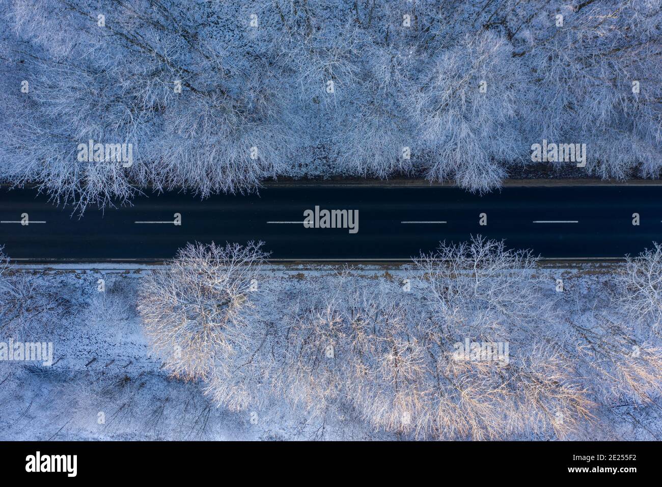 Csesznek, Hungary - Aerial top down view of winter forest crossed by asphalt road. Snowy landscape background. Stock Photo