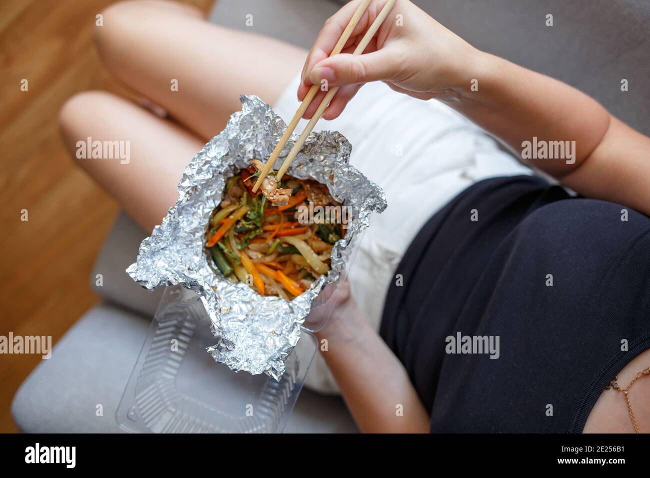 Young woman eating chinese take away food at home Stock Photo