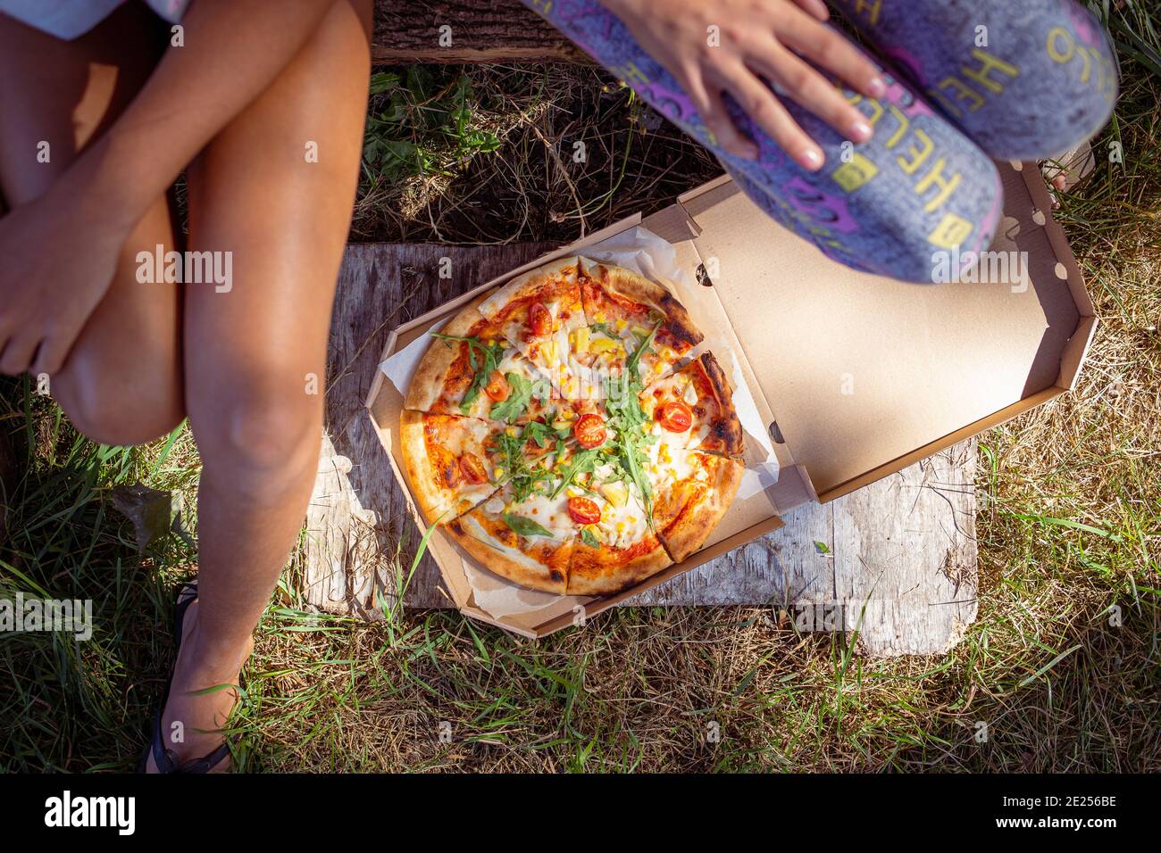 Two teenage girls sitting outdoor with pizza Stock Photo