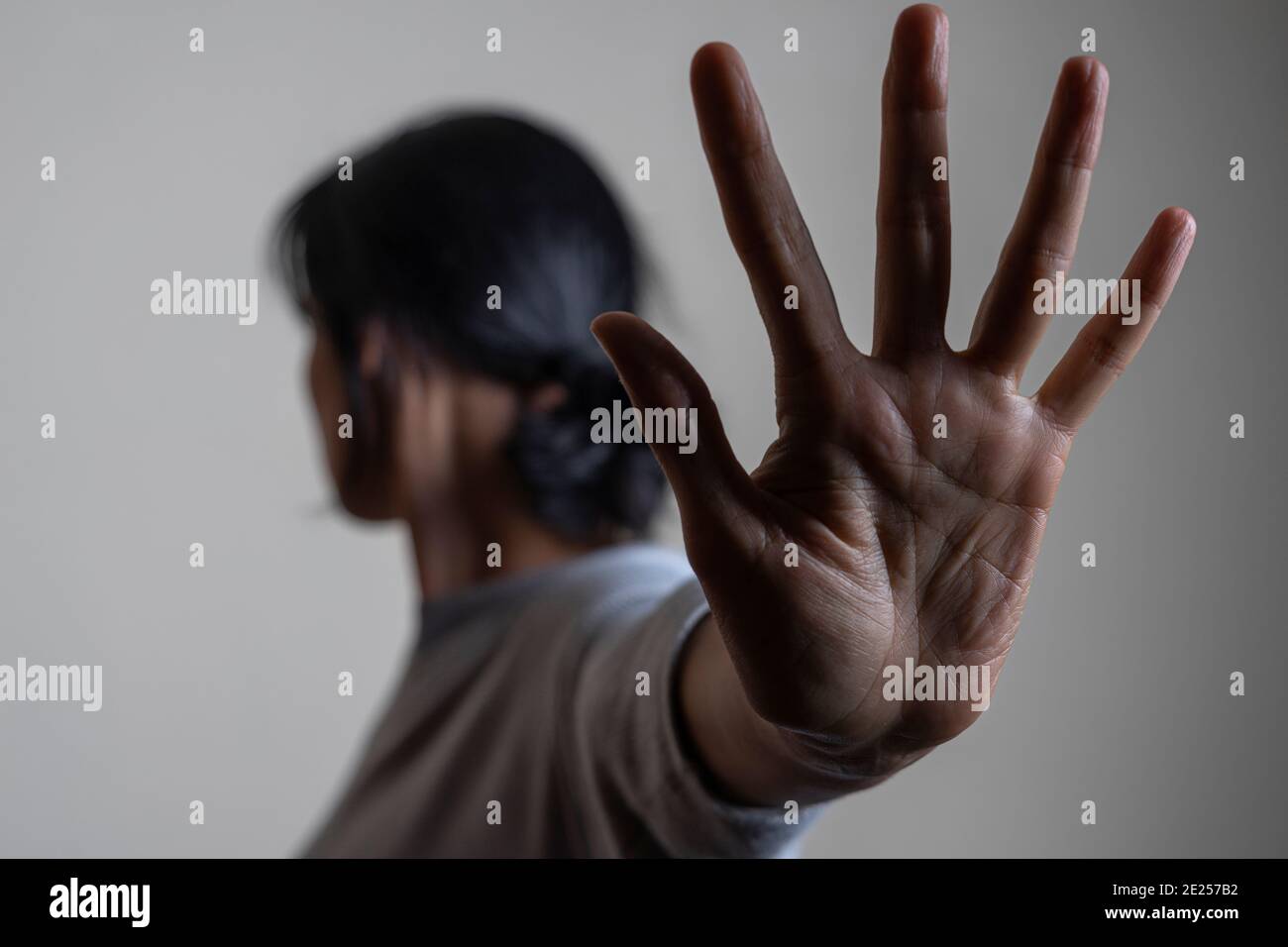 Woman rises her hand up and showes stop gesture by hand trying to stop any coming danger. Nonverbal language sign Stock Photo