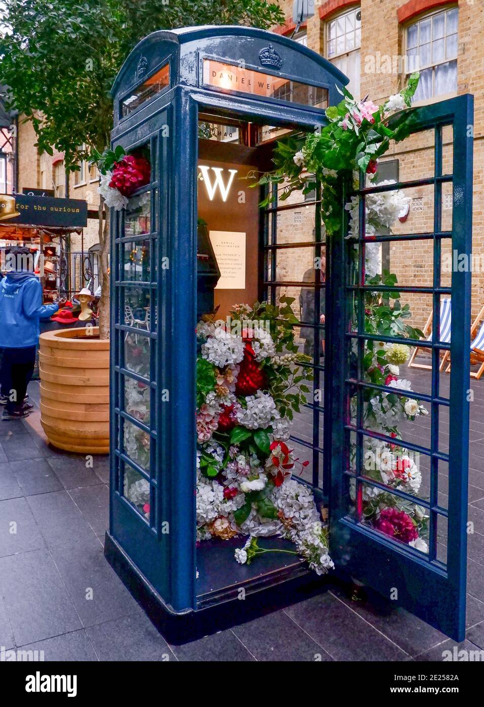 Flower decorated black phone booth with door open sponsored by Daniel  Wellington at Spitalfields Market, East London, UK Stock Photo - Alamy