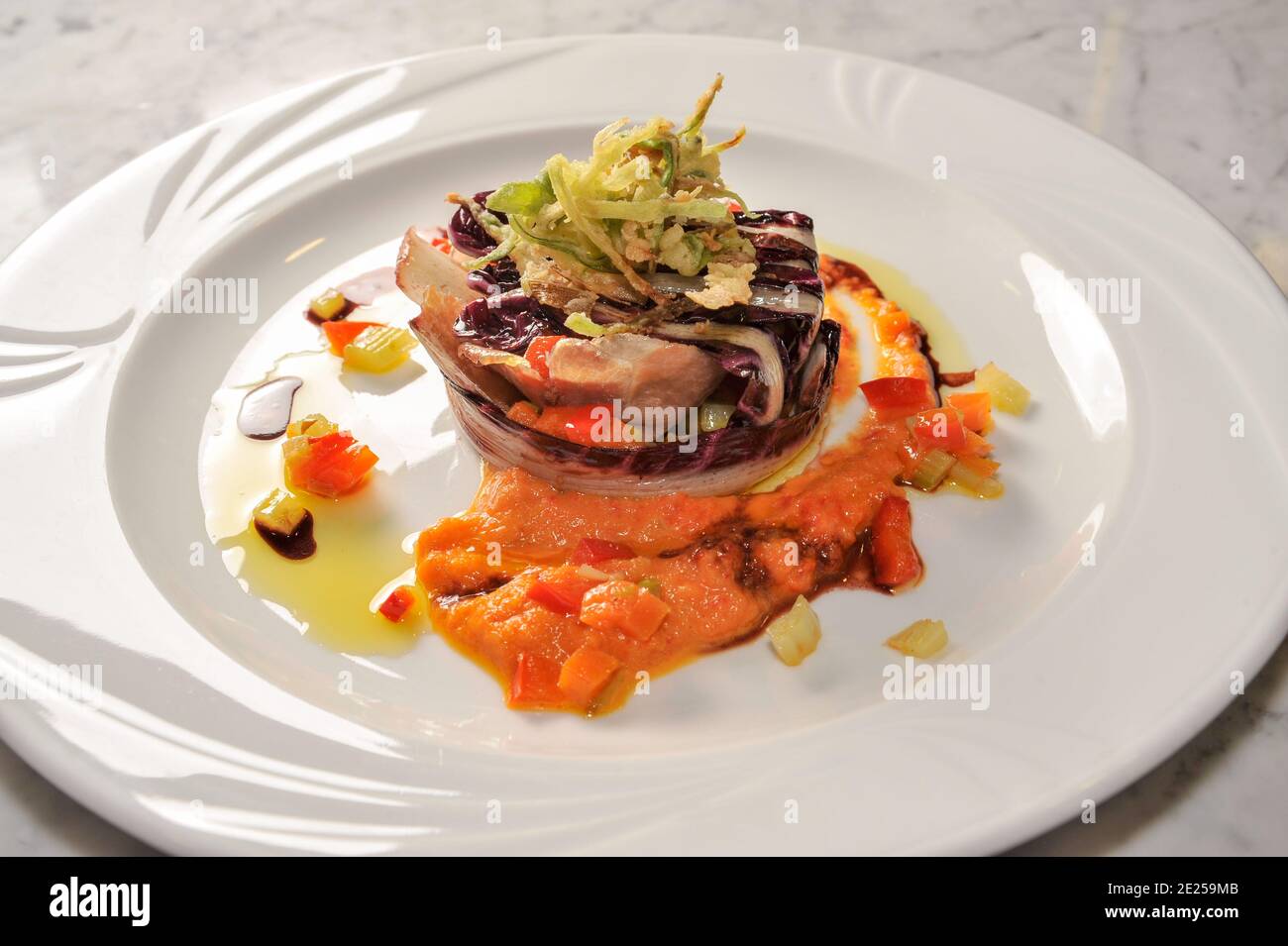 San Daniele ham in Treviso radicchio jacket with fried vegetables and tomato sauce in white dish, top view Stock Photo