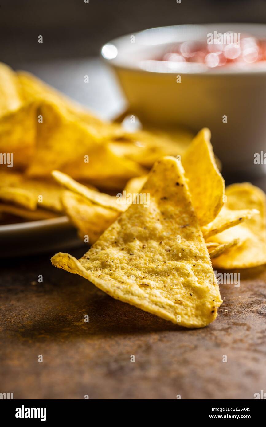 Tortilla chips and red tomato salsa dip. Mexican nacho chips on brown