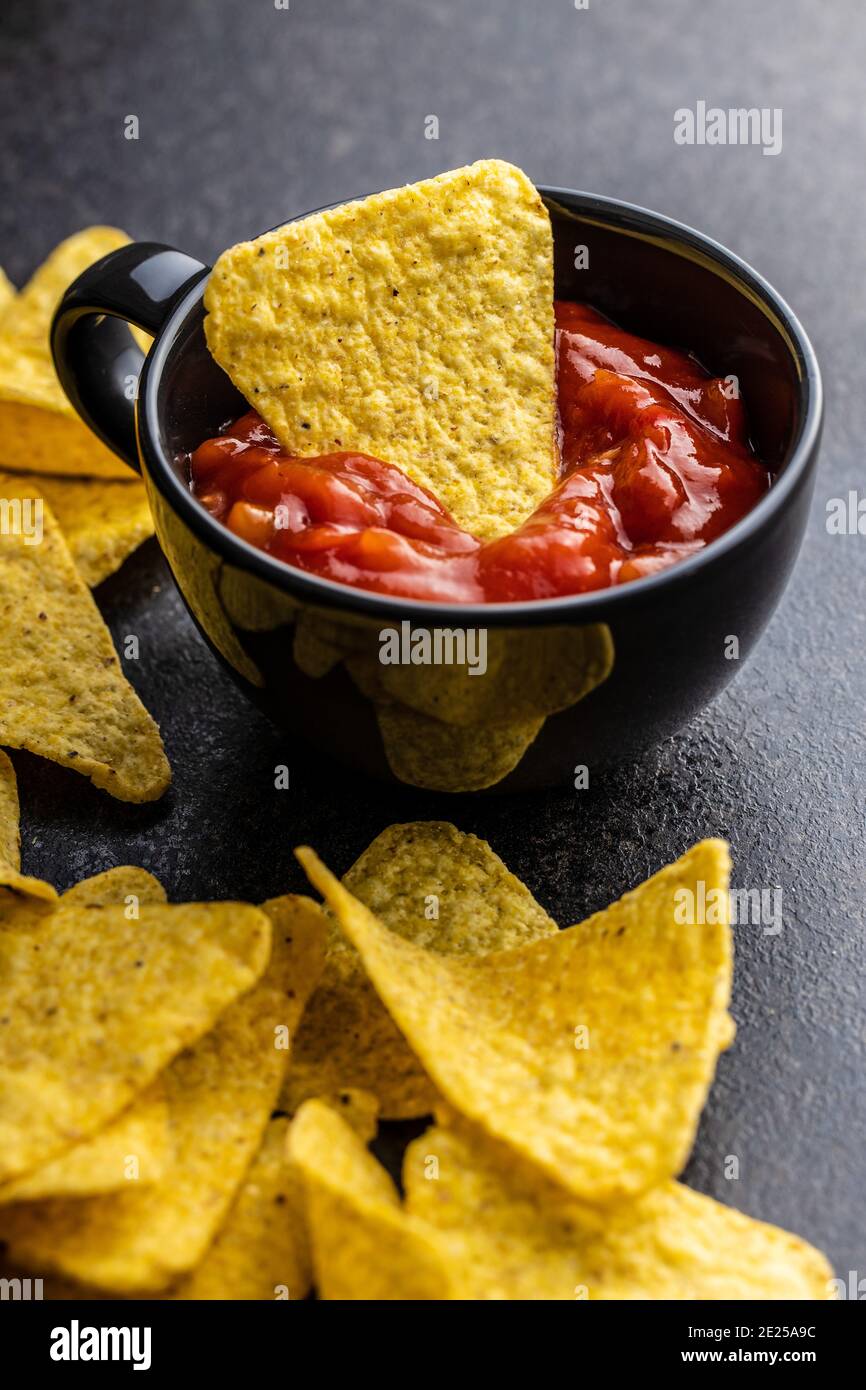 Tortilla chips and red tomato salsa dip. Mexican nacho chips on black