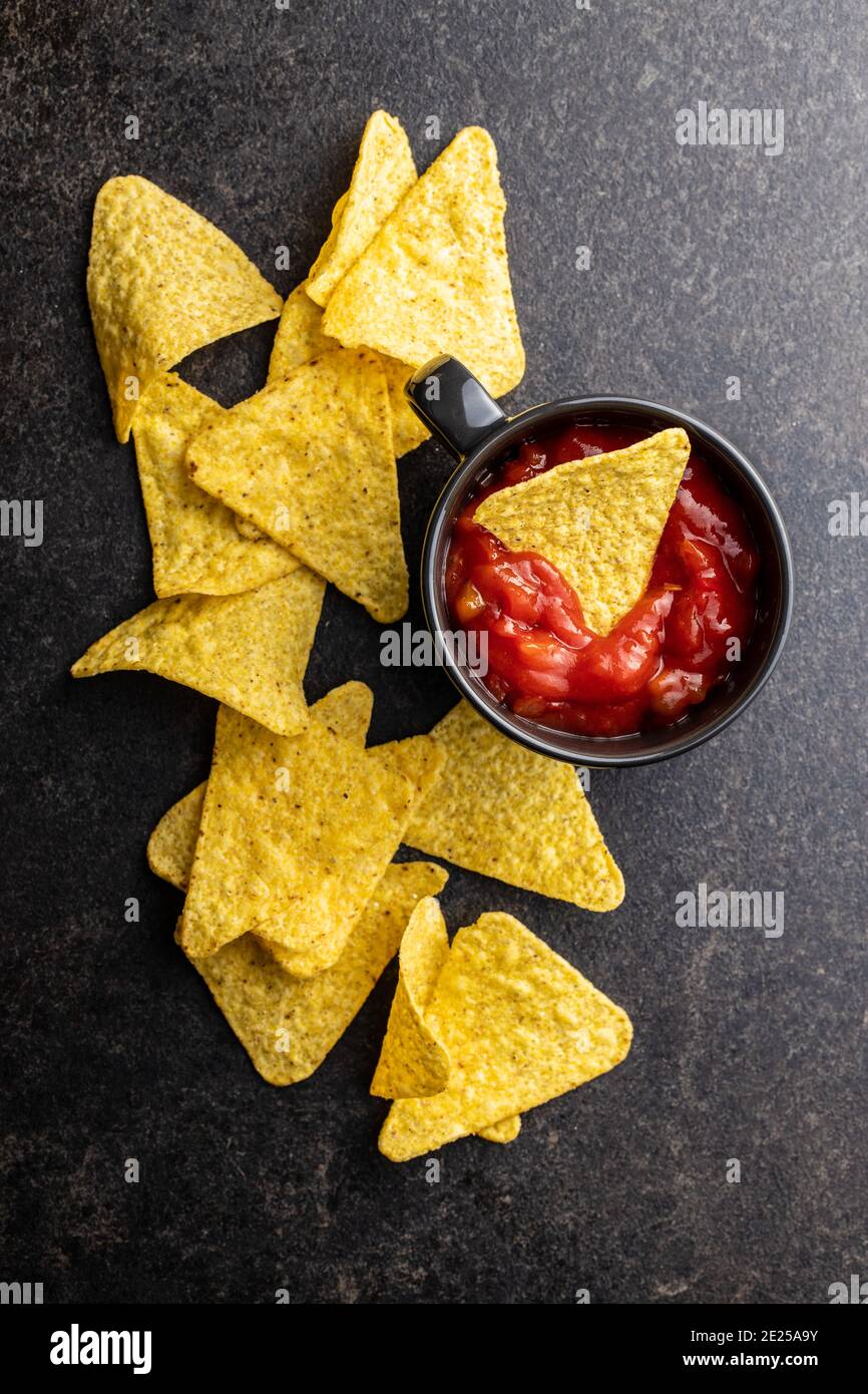 Tortilla chips and red tomato salsa dip. Mexican nacho chips on black