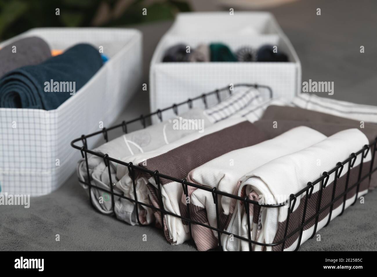 Vertical storage of clothing. Sorted clothes in baskets and shelves in a modern bedromm. Cleaning concept. Stock Photo