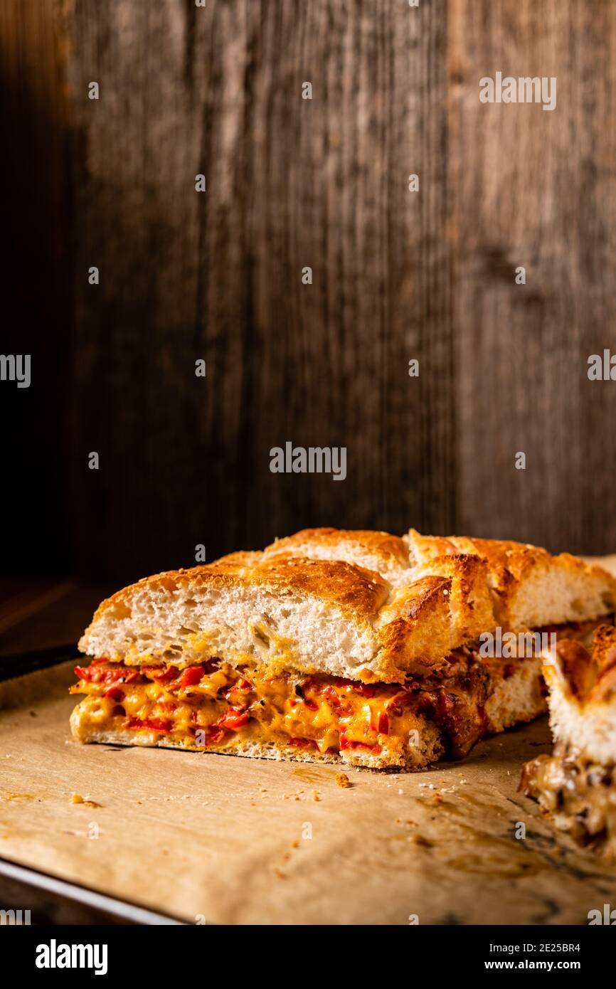 Grilled cheese sandwich with vegan cheese and red bell pepper in front of a rustic wooden background with copy space. Popular American fast food dish Stock Photo