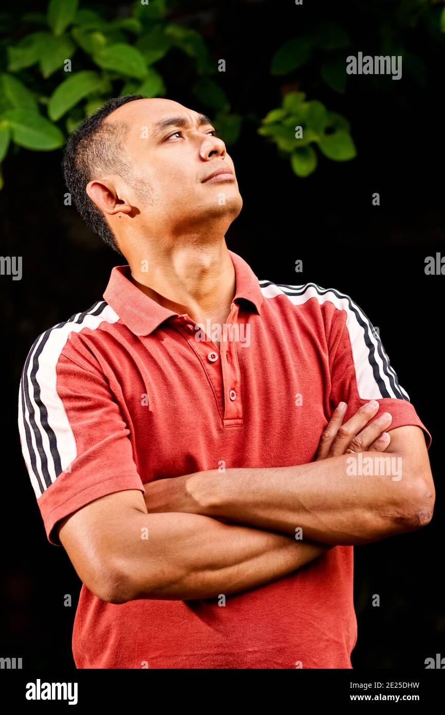 Portrait of a healthy and fit Southeast Asian ethnic young adult male looking up steadily with thoughtful expression Stock Photo