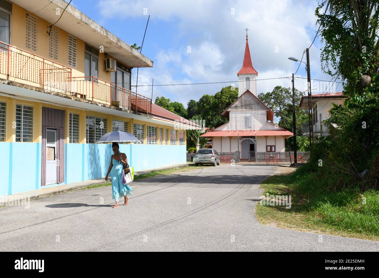 Guyana, Iracoubo: woman wearing a dress walking alone in a street, with the Church of Saint-Joseph in the background *** Local Caption *** Iracoubo; l Stock Photo