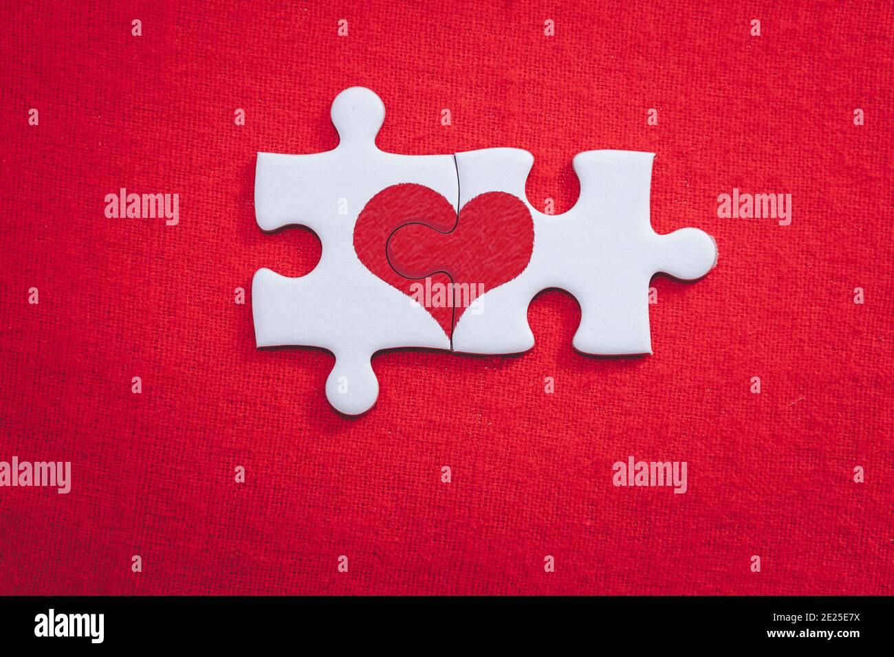 Heart shaped puzzle pieces love valentine concept for valentines day and sweetest day on red gift box background Stock Photo