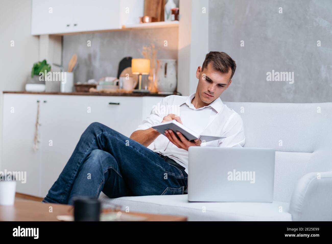 young man taking notes sitting on the couch . Stock Photo