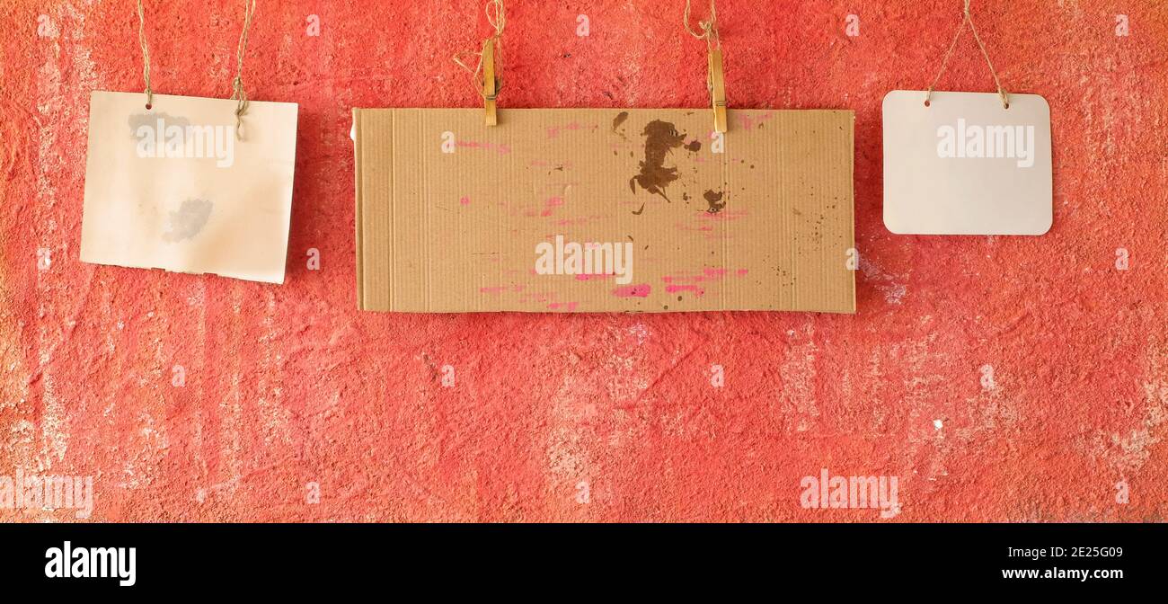 set of blank grungy cardboard signs or message boards  on grungy red wall, panoramic, free copy space Stock Photo