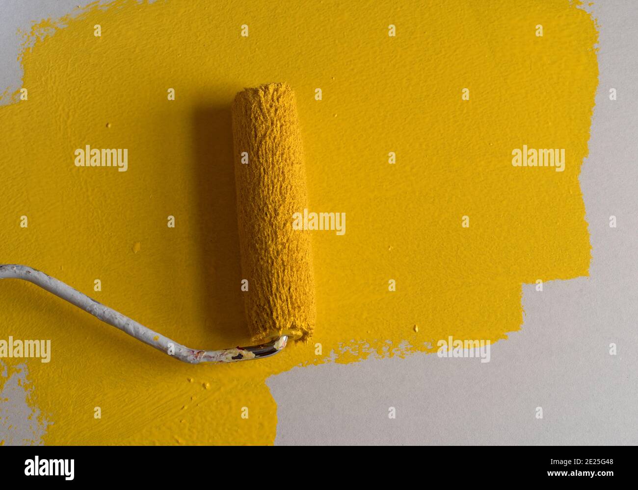 Using a small roller to paint yellow paint on a surface illuminated