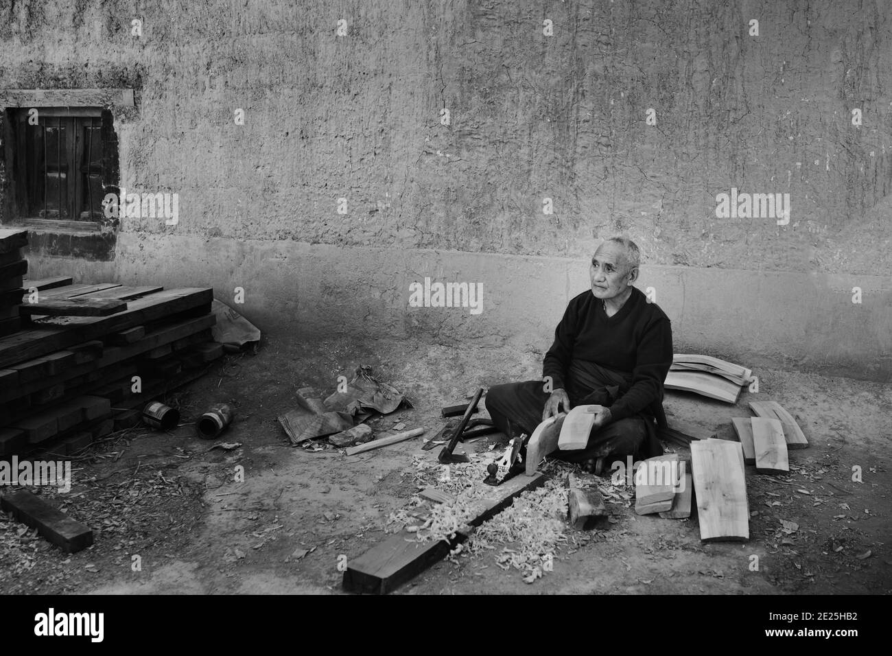 A Buddhist monk sitting lone working wood to make a barrel outside monastery in Tabo, Himachal Pradesh, India. Stock Photo