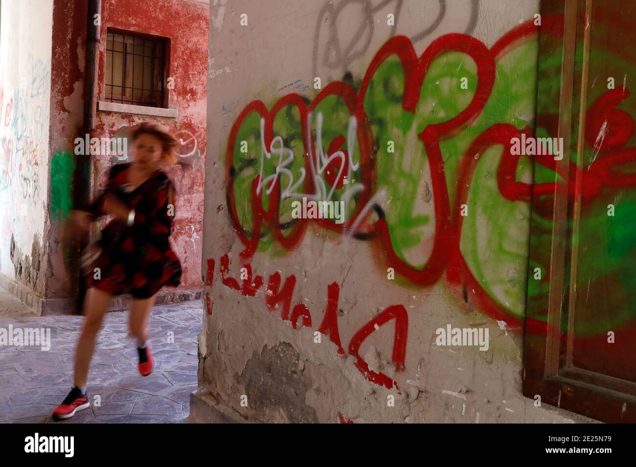 Woman runing by painted wall. Stock Photo