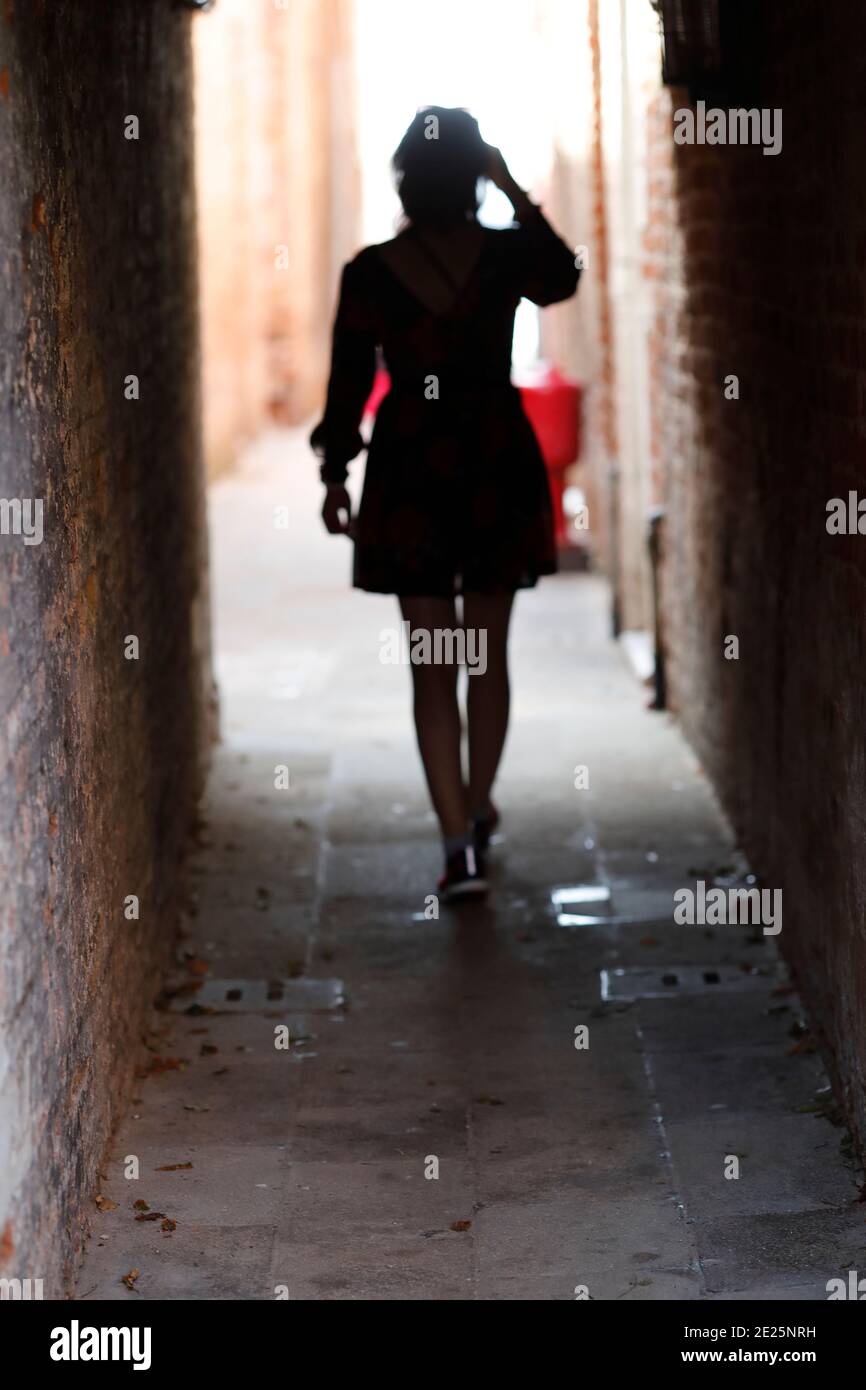 Silhouette of a woman  walking man on a narrow street. Stock Photo