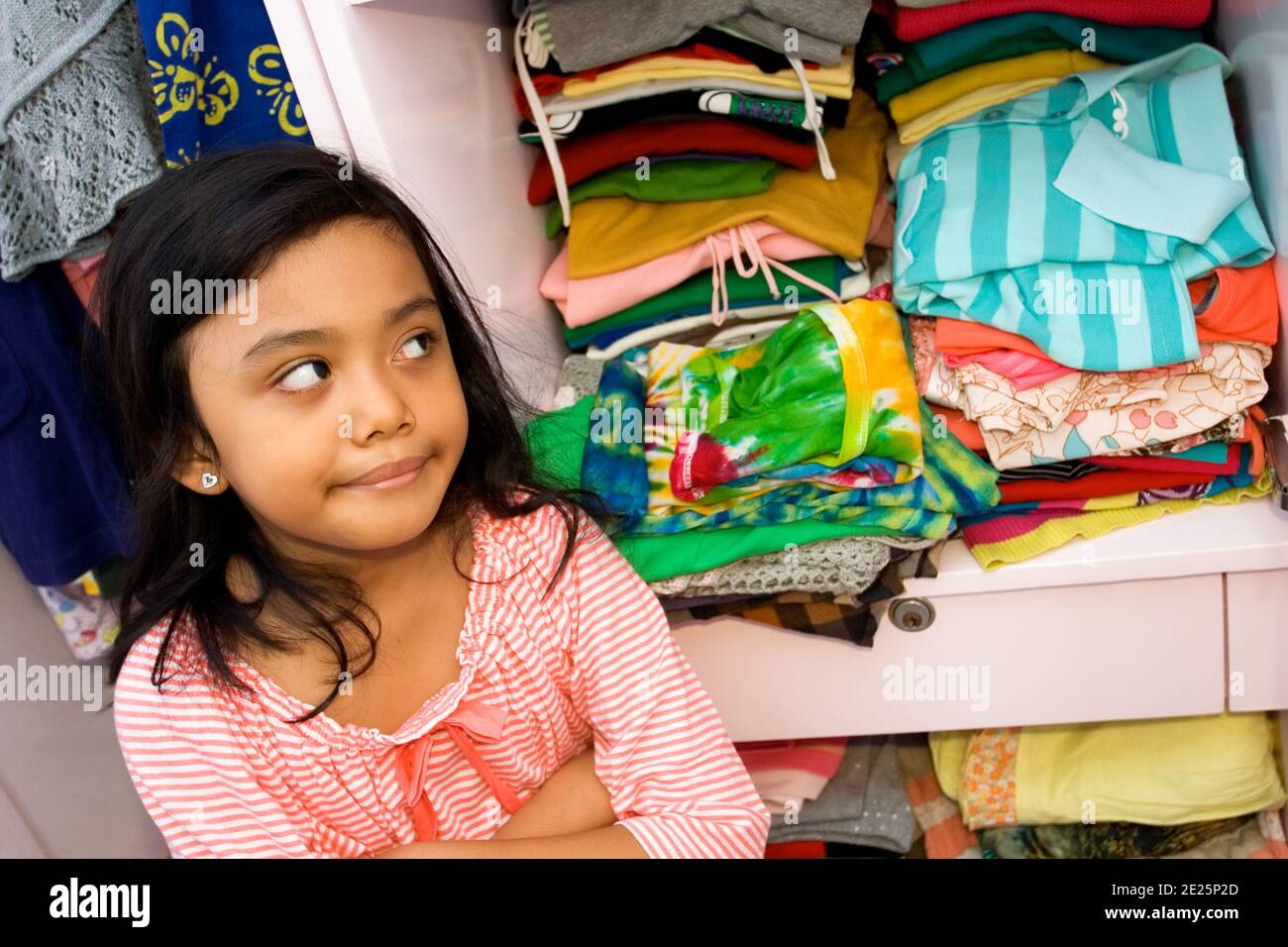 children lifestyle concept: sweet asian little girl showing her clothes collection in the clothes closet Stock Photo