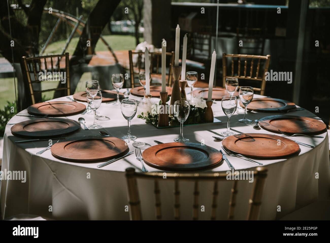 Table with white tablecloth, wooden plates and candles Stock Photo - Alamy