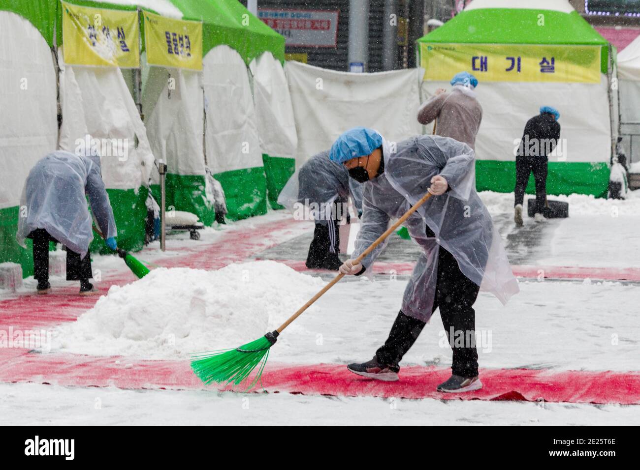 Bucheon, South Korea. 12th Jan, 2021. Workers at a coronavirus testing center in front of Bucheon Station in South Korea clean snow from the facility Tuesday. Credit: Jintak Han/ZUMA Wire/Alamy Live News Stock Photo