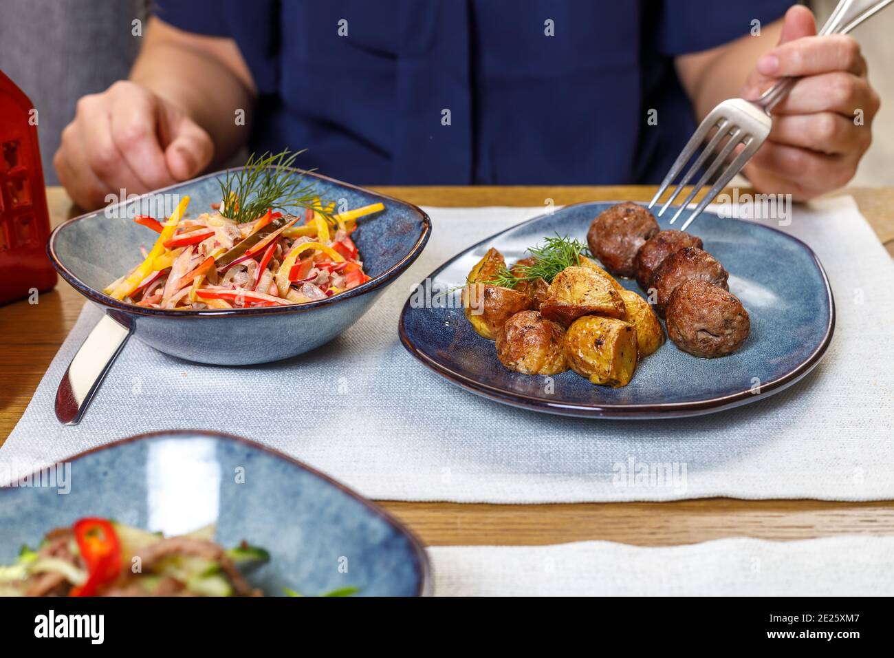 A fragment of the table setting in a restaurant or cafe. Salad, first and second course. The concept of the business lunch. Stock Photo