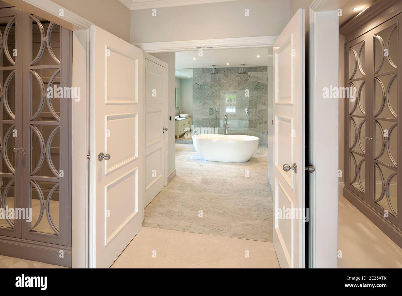 Mirrored dressing room through open doors down corridor to contemporary bathroom Stock Photo