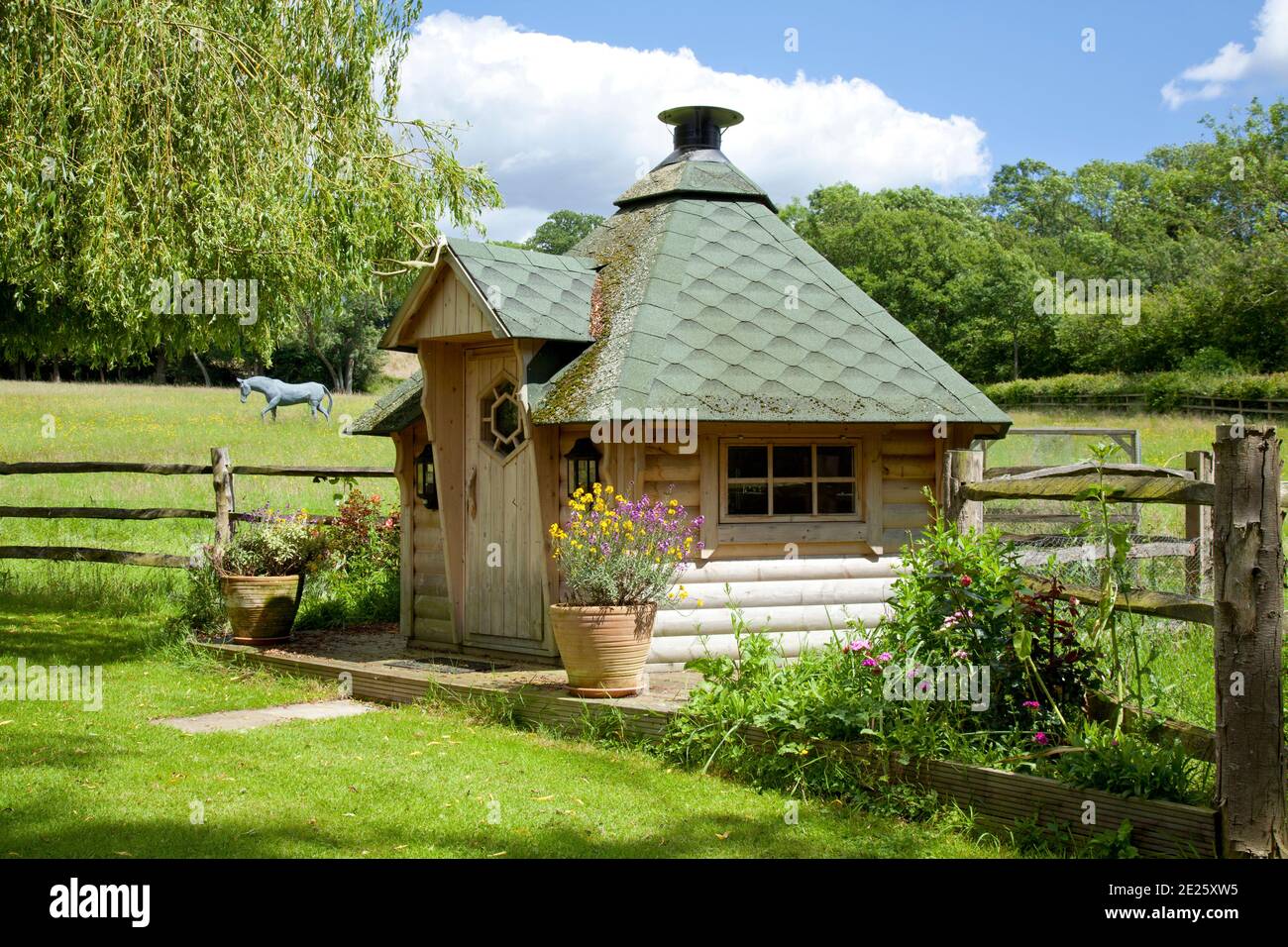Barbeque hut in garden with field and horse sculpture behind Stock Photo