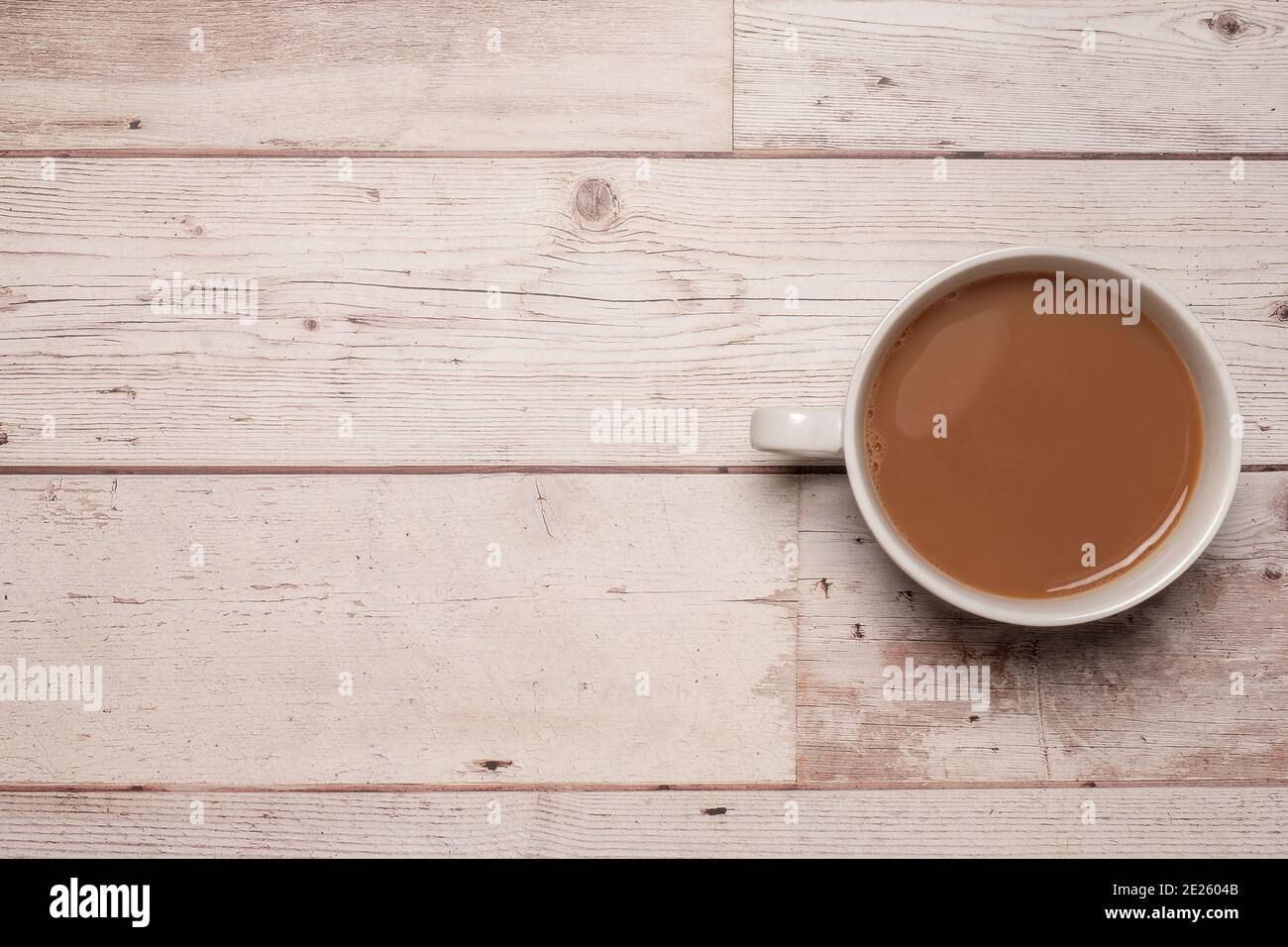 Cup of strong tea or coffee with milk in a white mug on a textured white wooden table surface with copy space and room for text. Stock Photo