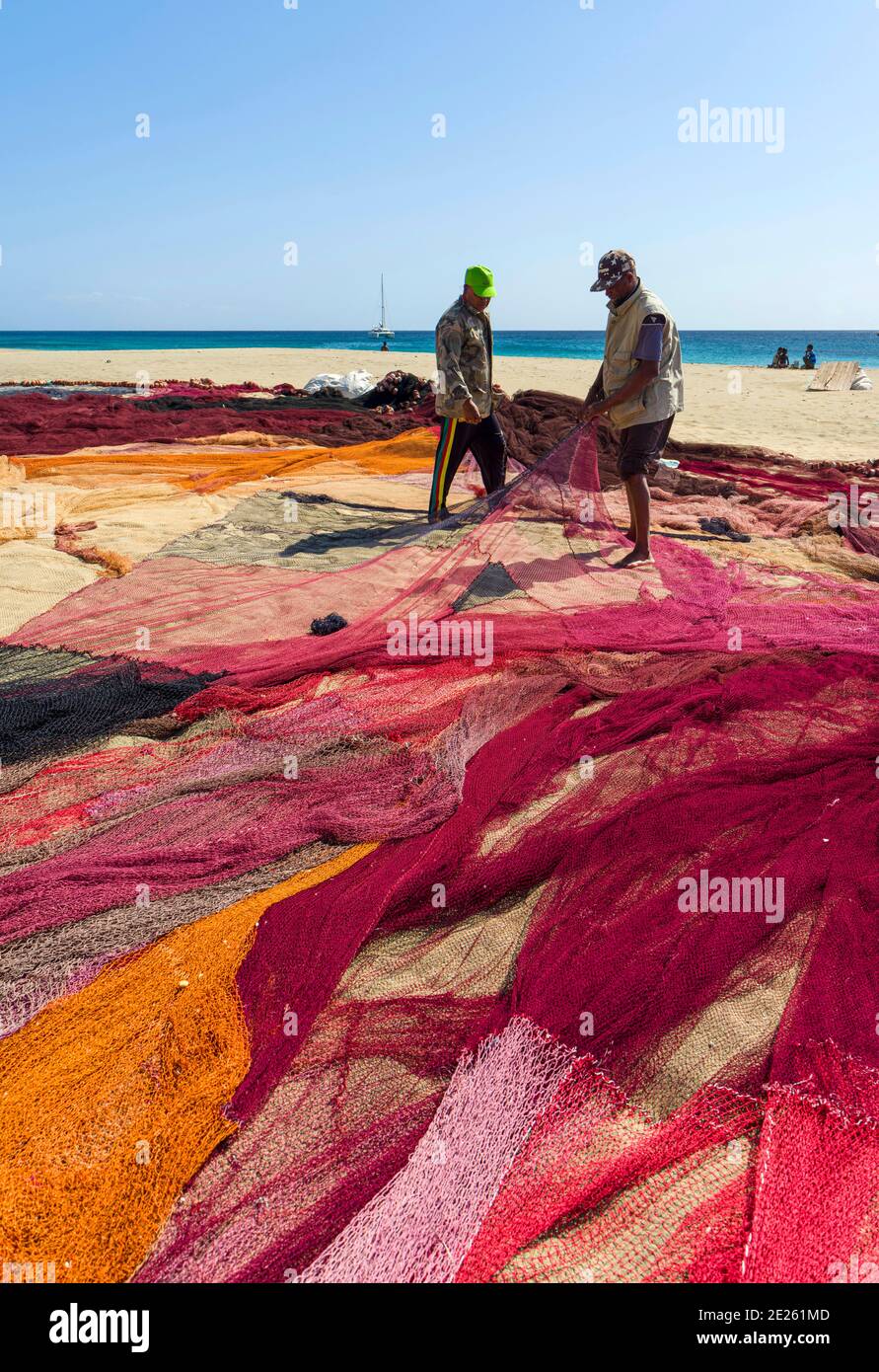 Fishermen are mending their colorful fishing nets on a beach near Sao ...