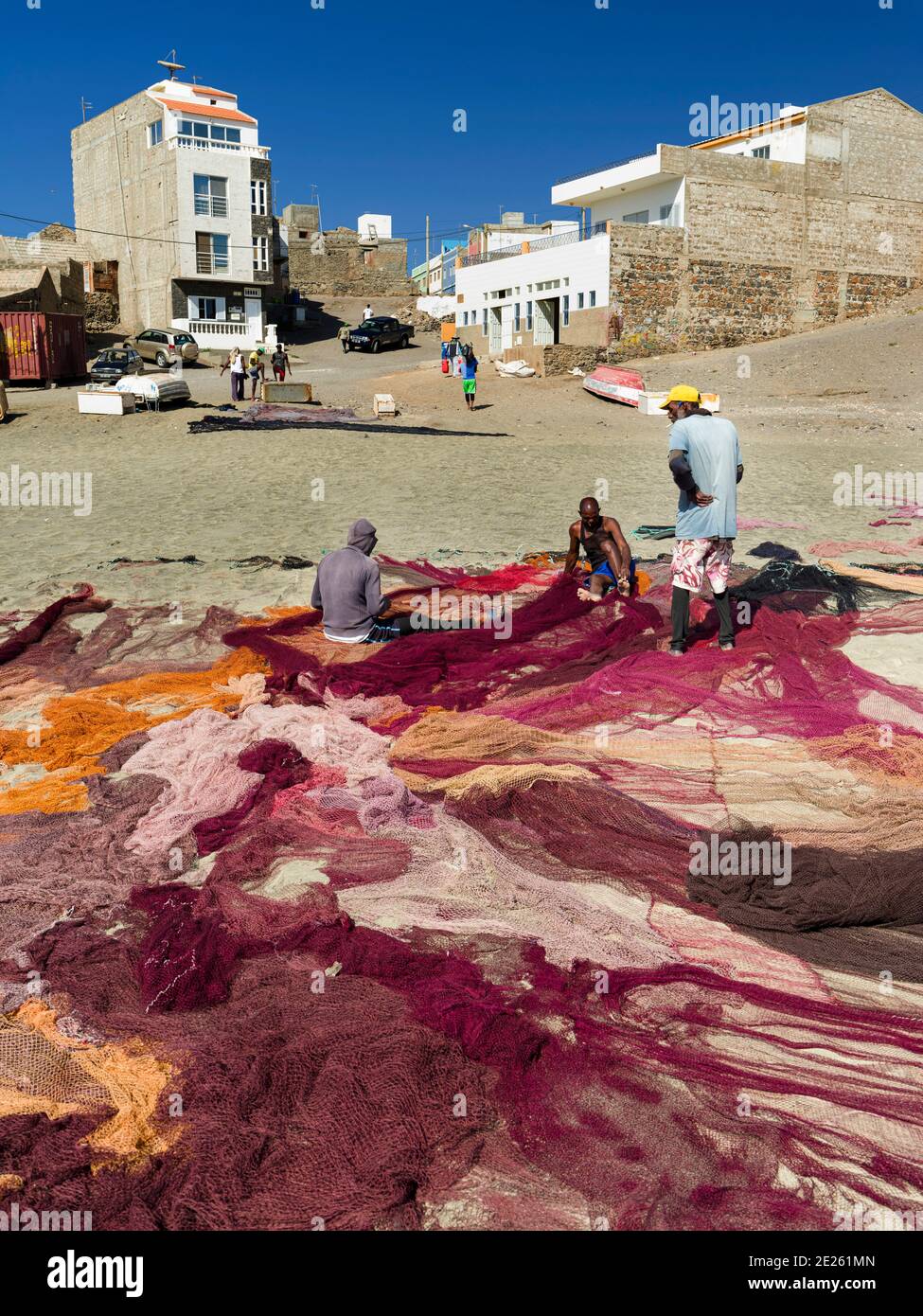 Fishermen are mending their colorful fishing nets on a beach near Sao ...
