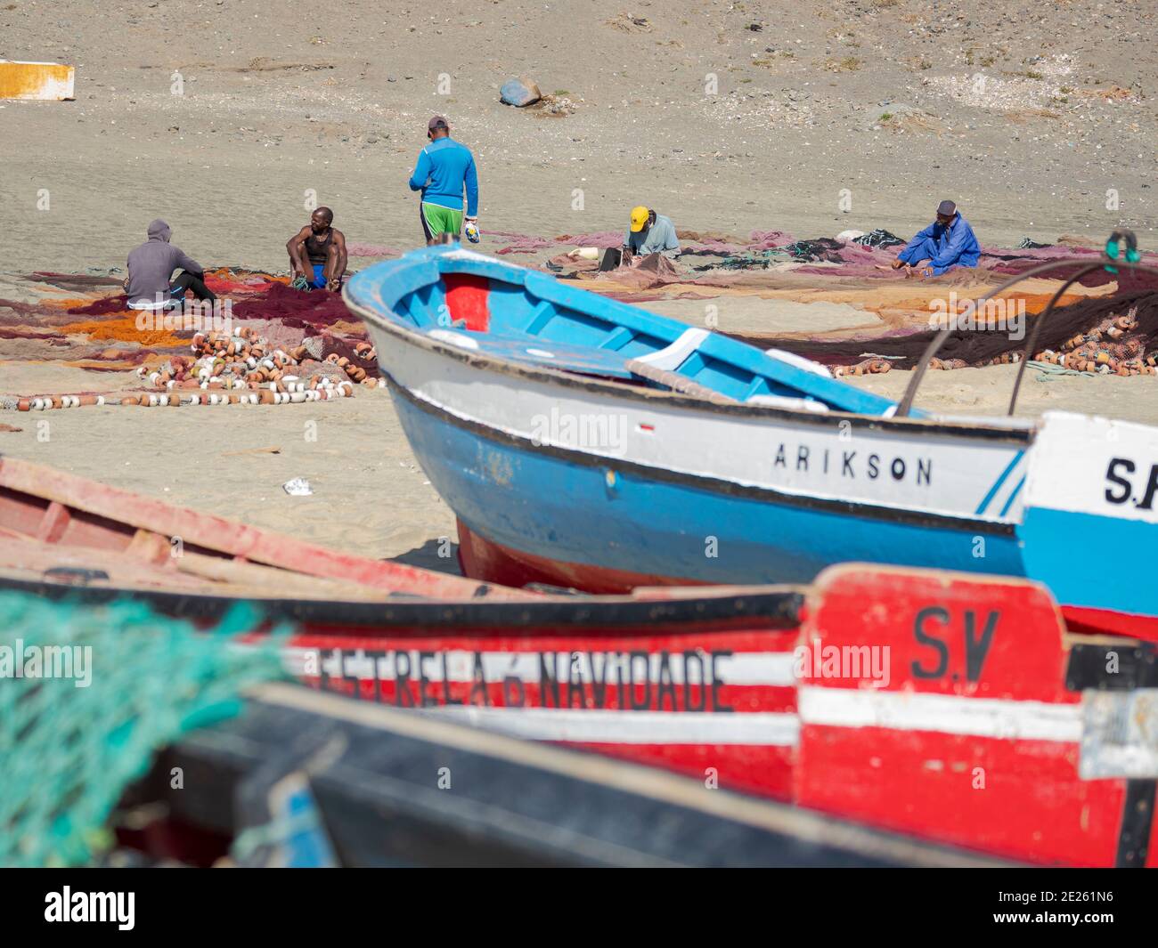 Fishermen are mending their colorful fishing nets on a beach near Sao ...
