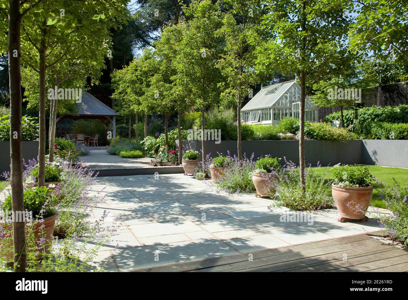Contemporary formal garden with tree lined path to gazebo and greenhouse Stock Photo