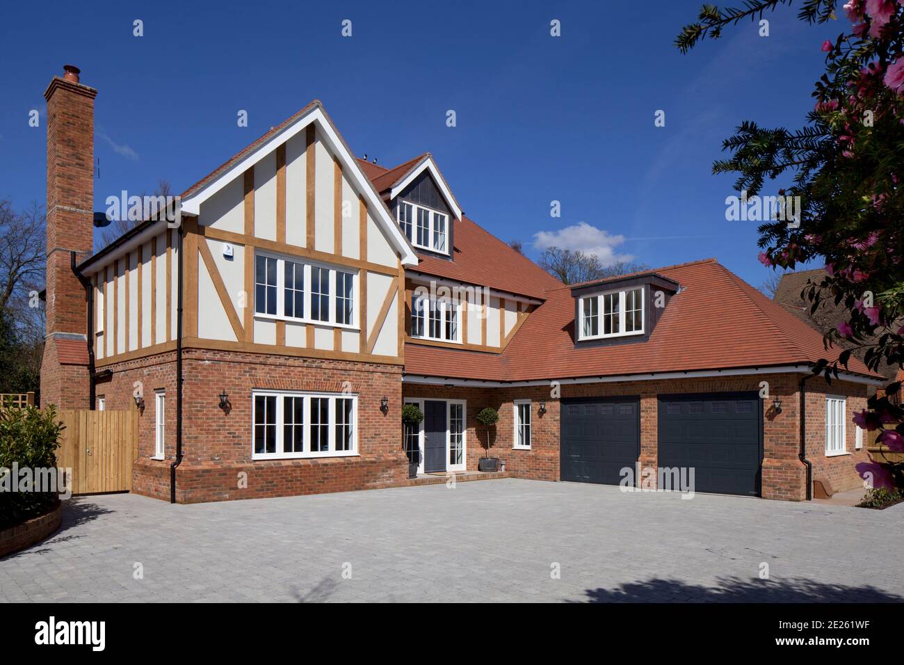 Large brick and timber-framed new build private family house with double garage and grey doors Stock Photo