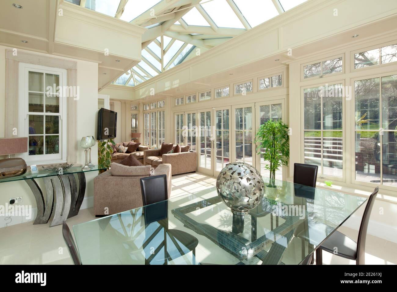 Orangery or conservatory extension with glass dining table and brown