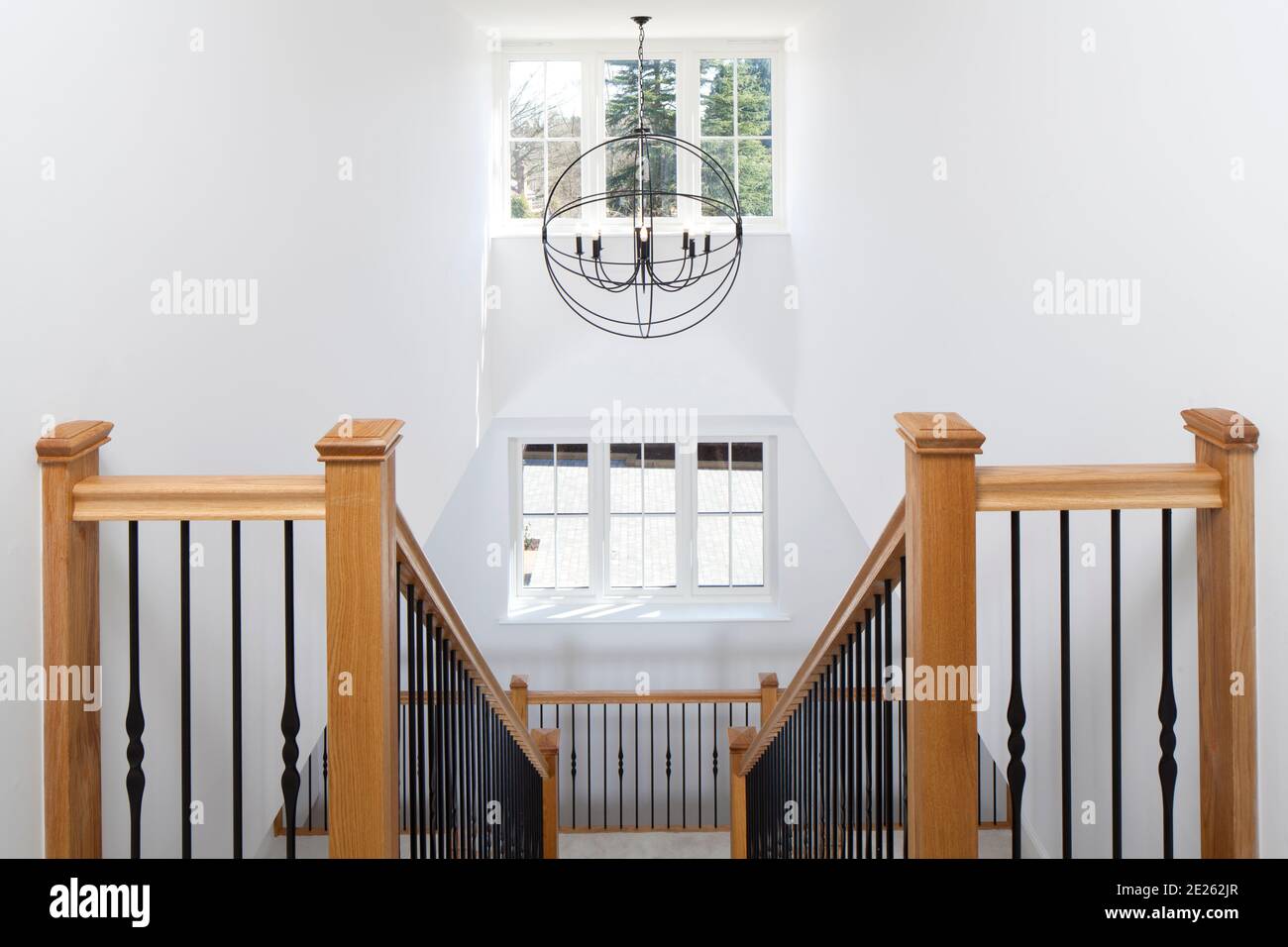 Symmetrical wood and wrought iron stairwell atrium with globe lantern in new house Stock Photo