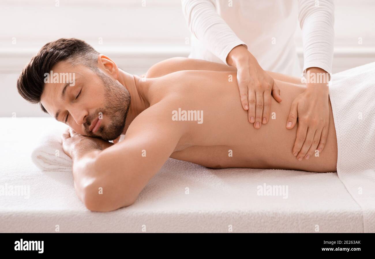Spa Body Massage. Close Up Beautiful Sexy Healthy Happy Man Enjoying  Relaxing Back Massage In Outdoor Day Beauty Salon. Masseur Hand Massaging  Male With Aromatherapy Oil. Skin Care Treatment Concept Stock Photo