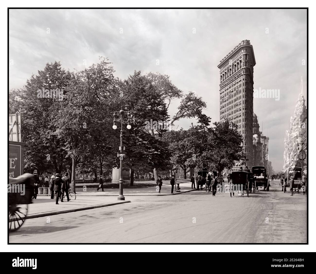 Vintage B&W 1900's Flatiron Building and Madison Square Park New York, with horse drawn carriages Manhattan USA 1906 The Flatiron Building, is a triangular 22-story, 285-foot-tall  steel-framed landmarked building located at 175 Fifth Avenue in the Flatiron District neighborhood of the borough of Manhattan, New York City. Designed by Daniel Burnham and Frederick Dinkelberg, Stock Photo