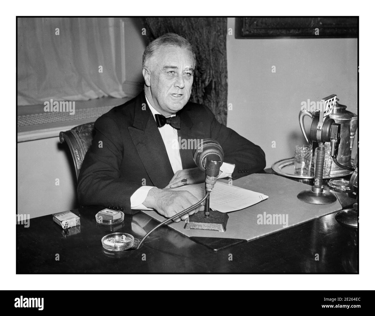 1930's FDR Franklin D. Roosevelt giving a radio broadcast (“fireside chat”) September 1934. On his desk CBS & NBC network broadcast microphones. Franklin Delano Roosevelt Sr., often referred to by his initials FDR, was an American statesman and political leader who served as the 32nd President of the United States from 1933 until his death in 1945. Stock Photo