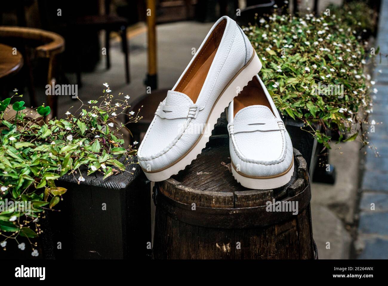 White leather moccasins. Photo on the street next to the flowers. Trendy white  loafers. Fashionable women's leather shoes Stock Photo - Alamy