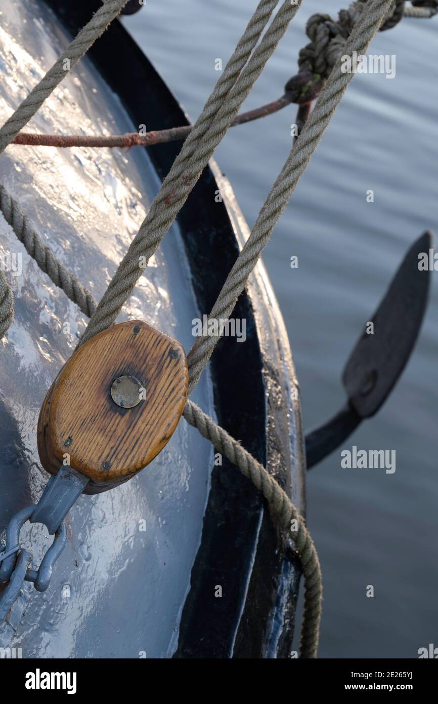 Brown wooden pulley with ropes on the bow of a ship. Focus on the wood of the pulley. Narrow depth of field Stock Photo
