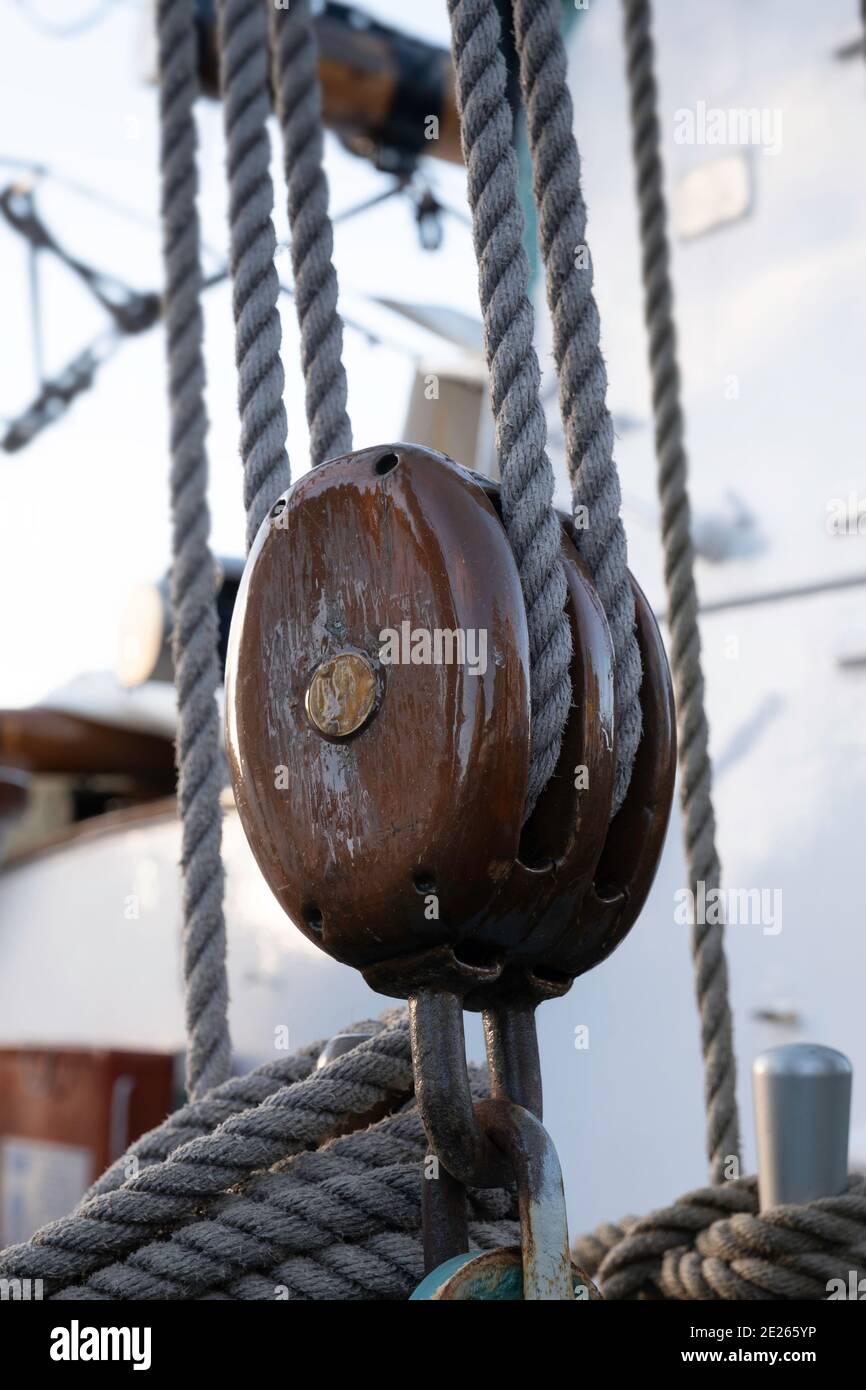 Brown wooden pulley with ropes on a ship. Focus on the wood of the pulley Stock Photo