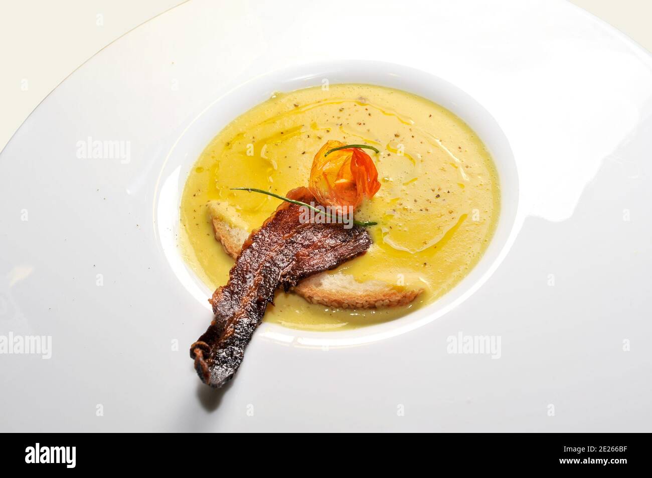 cheese fondue with slice of roasted bacon and slice of bread in white plate Stock Photo