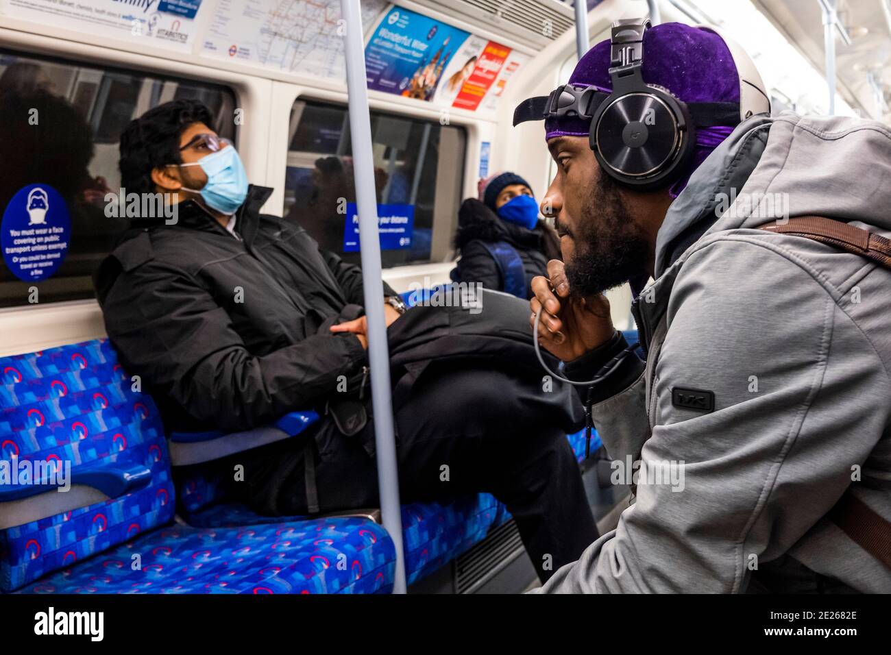 London, UK. 12th Jan, 2021. A woman in a mask tries to get the attention of an unmasked man, who ignores her as he appears to be talking to someone on his phone - The underground is still fairly busy despite the new national Lockdown, Stay at Home, instructions. Most travellers wear masks as they are already mandatory. Credit: Guy Bell/Alamy Live News Stock Photo