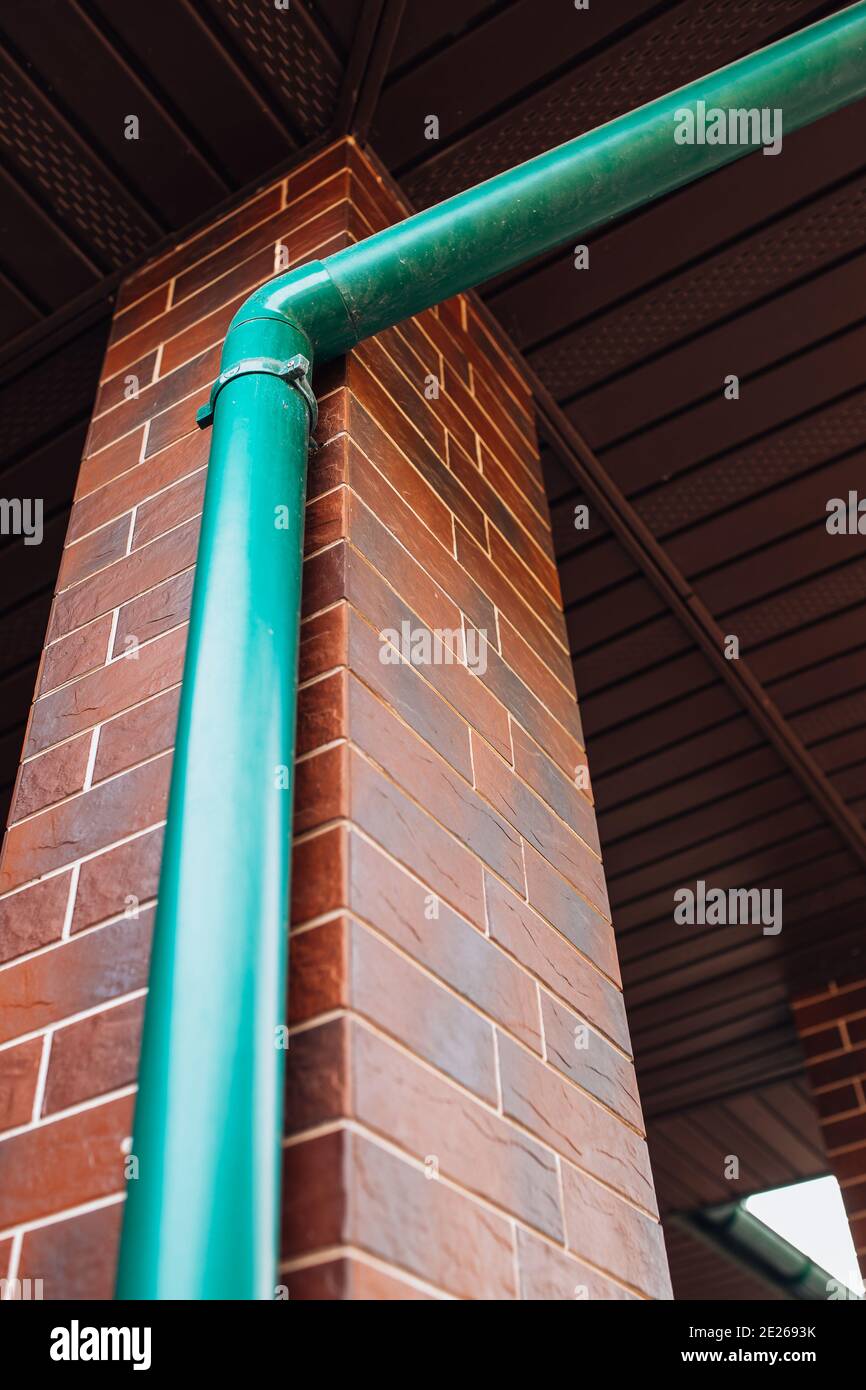 Plastic green drainage pipe on the wall of the house to drain water
