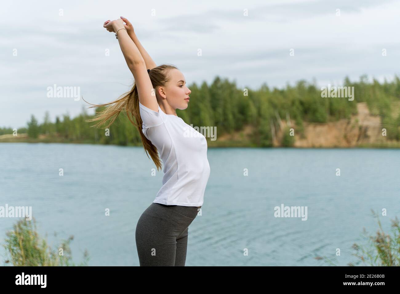 Slender girl doing yoga on the shore of the lake Stock Photo