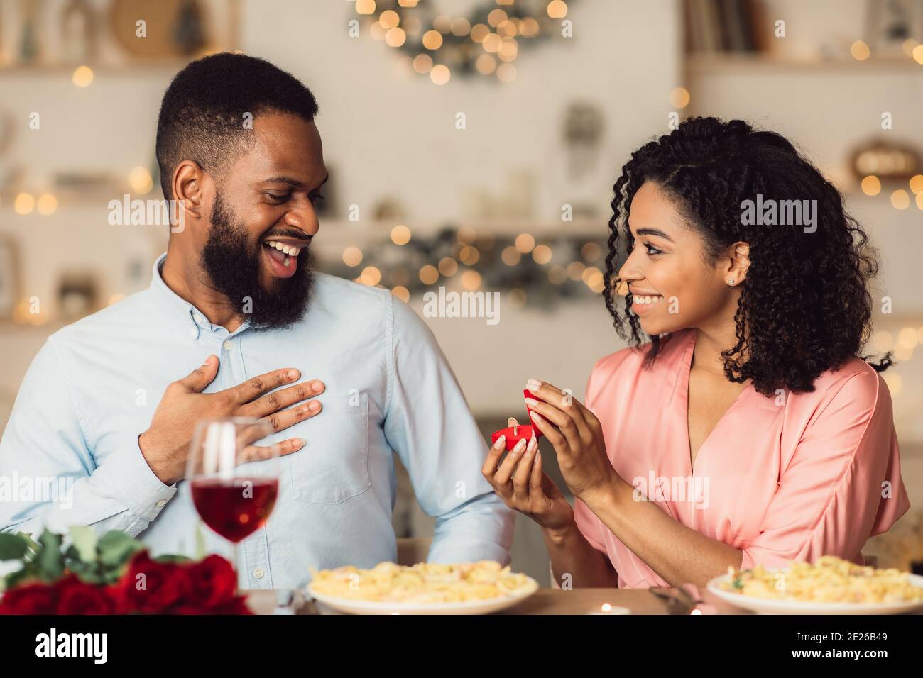 Smiling black woman making proposal with ring to her man Stock Photo